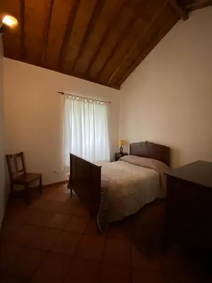 a bedroom with a bed and a chair and a window at Casa da Avó - Turismo Rural in Santo Espírito
