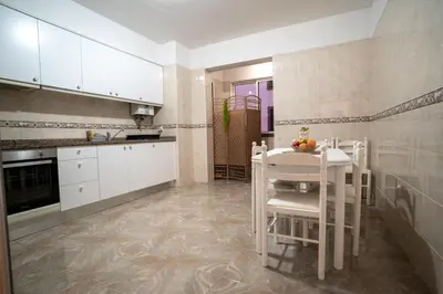 a kitchen with white cabinets and a white table and chairs at Apartamento Brava JT in Ribeira Brava