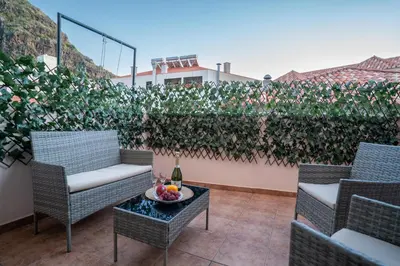 a patio with chairs and a table with a bottle of wine at Apartamento Brava JT in Ribeira Brava