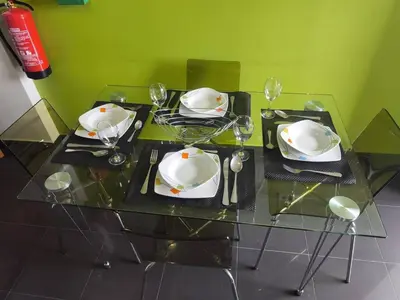 a glass table with plates and wine glasses on it at Alojamiento Local - Nilia in Caniço