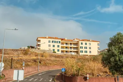 a building on the side of a hill with a road at Caniço Horizon Apartment by Amazing Madeira in Caniço