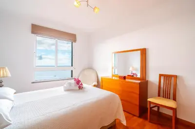 a bedroom with a bed and a dresser and a mirror at Caniço Horizon Apartment by Amazing Madeira in Caniço