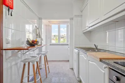 a kitchen with white cabinets and a counter with stools at Our Nest by ALMA Holiday Rentals in Caniço