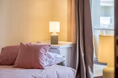 a bed with a lamp on a nightstand next to a window at Nata7 Apartment in Funchal