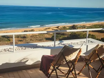 two chairs sitting on a balcony overlooking the beach at Sunny seaside stay in Vila Baleira