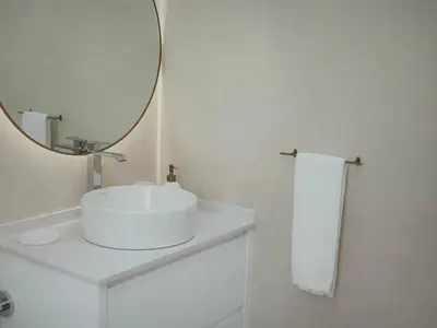 a white bathroom with a sink and a mirror at Sunny seaside stay in Vila Baleira
