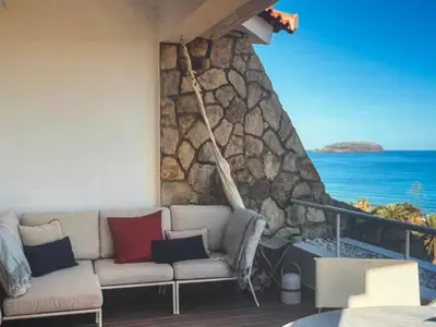 a living room with a couch and a stone wall at Sunny seaside stay in Vila Baleira
