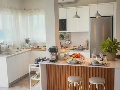 a kitchen with white cabinets and a counter with stools at Sunny seaside stay in Vila Baleira