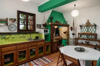 a kitchen with a white table and a green wall at Antiga Fábrica da Manteiga by An Island Apart in Arco da Calheta