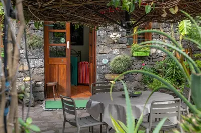 a table and chairs in front of a stone building at Antiga Fábrica da Manteiga by An Island Apart in Arco da Calheta