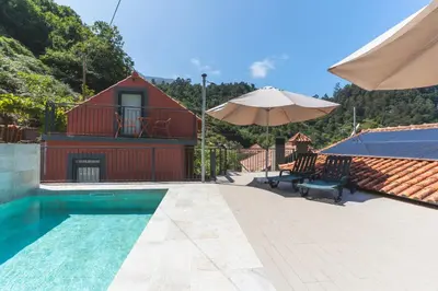 a house with a swimming pool and an umbrella at Avo Maria House by AH in São Vicente