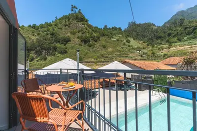 a balcony with a table and chairs and a pool at Avo Maria 2 House by AH in São Vicente