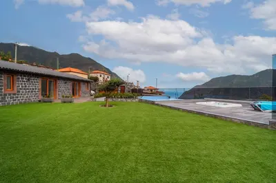 a yard with a green lawn in front of a house at Vilaugusto in São Vicente