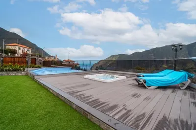 a patio with a swimming pool and a blue umbrella at Vilaugusto in São Vicente