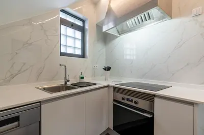 a kitchen with white chairs and a counter with black cabinets at Rodrigues House - Private Jacuzzi in Calheta