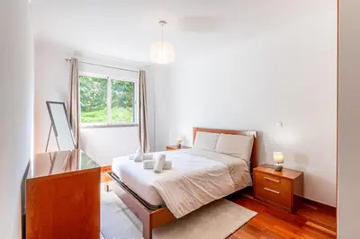 a bedroom with a bed and a desk and a window at Brisa do Caniço in Caniço