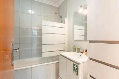 a white bathroom with a sink and a shower at Brisa do Caniço in Caniço