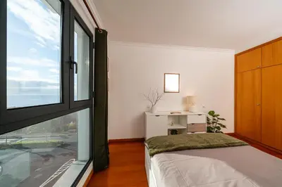 a bedroom with a bed and a large window at Chill'Inn Madeira in Santa Cruz