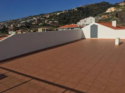 a tile roof with a white wall and a mountain at Chill'Inn Madeira in Santa Cruz