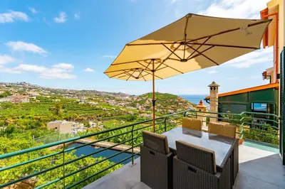a balcony with a table and an umbrella at JPL - Preces Residential in Câmara de Lobos
