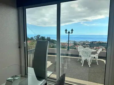 a balcony with a table and chairs and a view of the ocean at Casa de Ferias dos Marmeleiros in Funchal