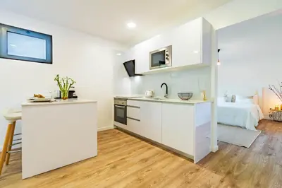 a kitchen with white cabinets and a bed in a room at Nobregas Lodge in Senhora do Rosário