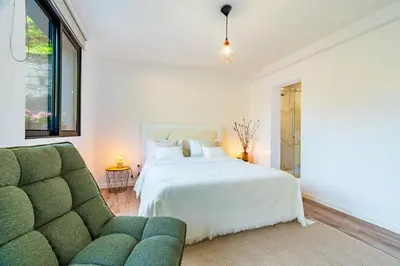 a white bedroom with a bed and a couch at Nobregas Lodge in Senhora do Rosário