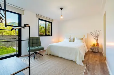 a bedroom with a white bed and a green chair at Nobregas Lodge in Senhora do Rosário