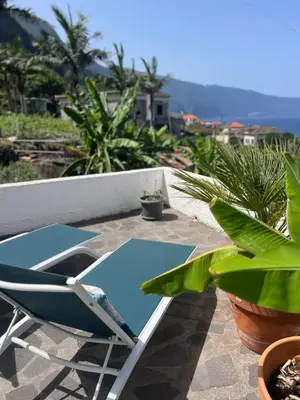 a chair on a patio with a view of the ocean at Loft - Villa Casa do mar in Ponta Delgada