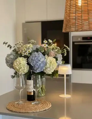 a bottle of wine and two wine glasses and flowers at Loft - Villa Casa do mar in Ponta Delgada