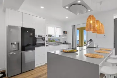 a white kitchen with a large island with a counter top at Loft - Villa Casa do mar in Ponta Delgada