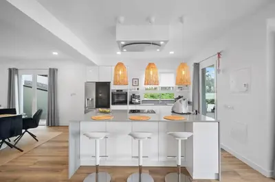 a white kitchen with a large island with bar stools at Loft - Villa Casa do mar in Ponta Delgada