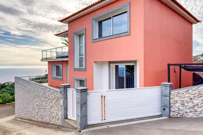 a red house with a white fence at Ponta do Sol Sea View, a Home in Madeira in Ponta do Sol