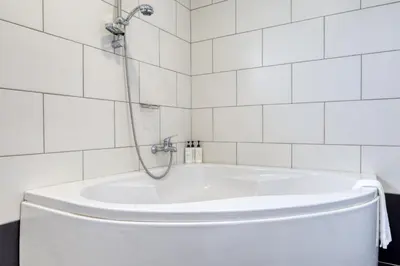 a white tub in a bathroom with white tiles at Ponta do Sol Sea View, a Home in Madeira in Ponta do Sol