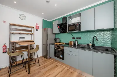 a kitchen with white cabinets and a table and chairs at Stylish 1 Bed Room Studio Flat in Funchal