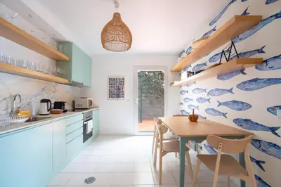 a kitchen with a wooden table and a blue and white wall at Villa Jasmin by Atlantic Holiday in Caniço