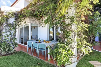 a patio with a table and chairs in a yard at Villa Jasmin by Atlantic Holiday in Caniço