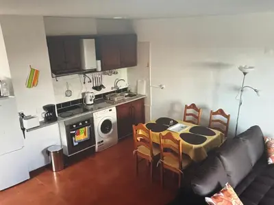 a living room with a kitchen and a table with chairs at Charming island in Ponta Delgada