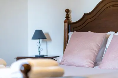 a bed with a pink pillow and a lamp on a table at GuestReady - Faia House in Gaula