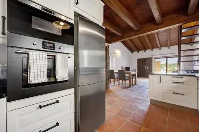a kitchen with white cabinets and a wooden ceiling at House Fun Ride Surf School in Sagres