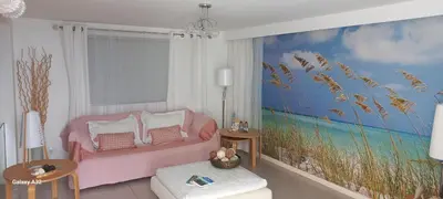 a living room with a pink couch and a painting of a beach at Crystal Madeira Studio in Funchal