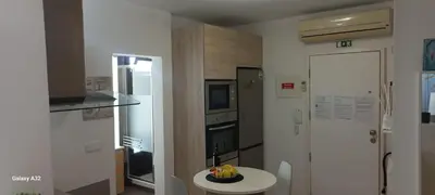 a white kitchen with a bowl of fruit on a table at Crystal Madeira Studio in Funchal