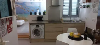 a kitchen with a washing machine and a bowl of fruit on a table at Crystal Madeira Studio in Funchal