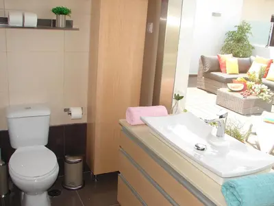 a bathroom with a sink and a toilet and a couch at Crystal Madeira Studio in Funchal