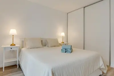a white bed with two blue pillows on it at Mercy by the Sea by Holiday Rental Madeira in Machico
