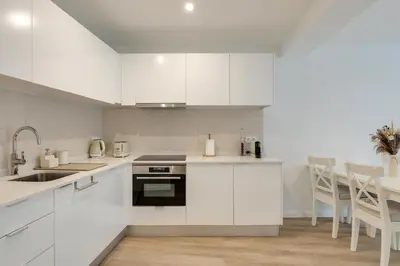 a white kitchen with white cabinets and a table at Mercy by the Sea by Holiday Rental Madeira in Machico