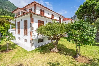 a white house with trees in front of it at Casa do Vale in São Vicente