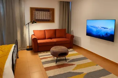 a living room with an orange couch and a chair at Frutti studio by Turin in Funchal