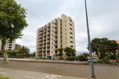 a tall white apartment building in front of a street at Frutti studio by Turin in Funchal