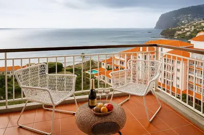 a balcony with chairs and a bottle of wine and a bowl of fruit at Tutti studio by Turin in Funchal